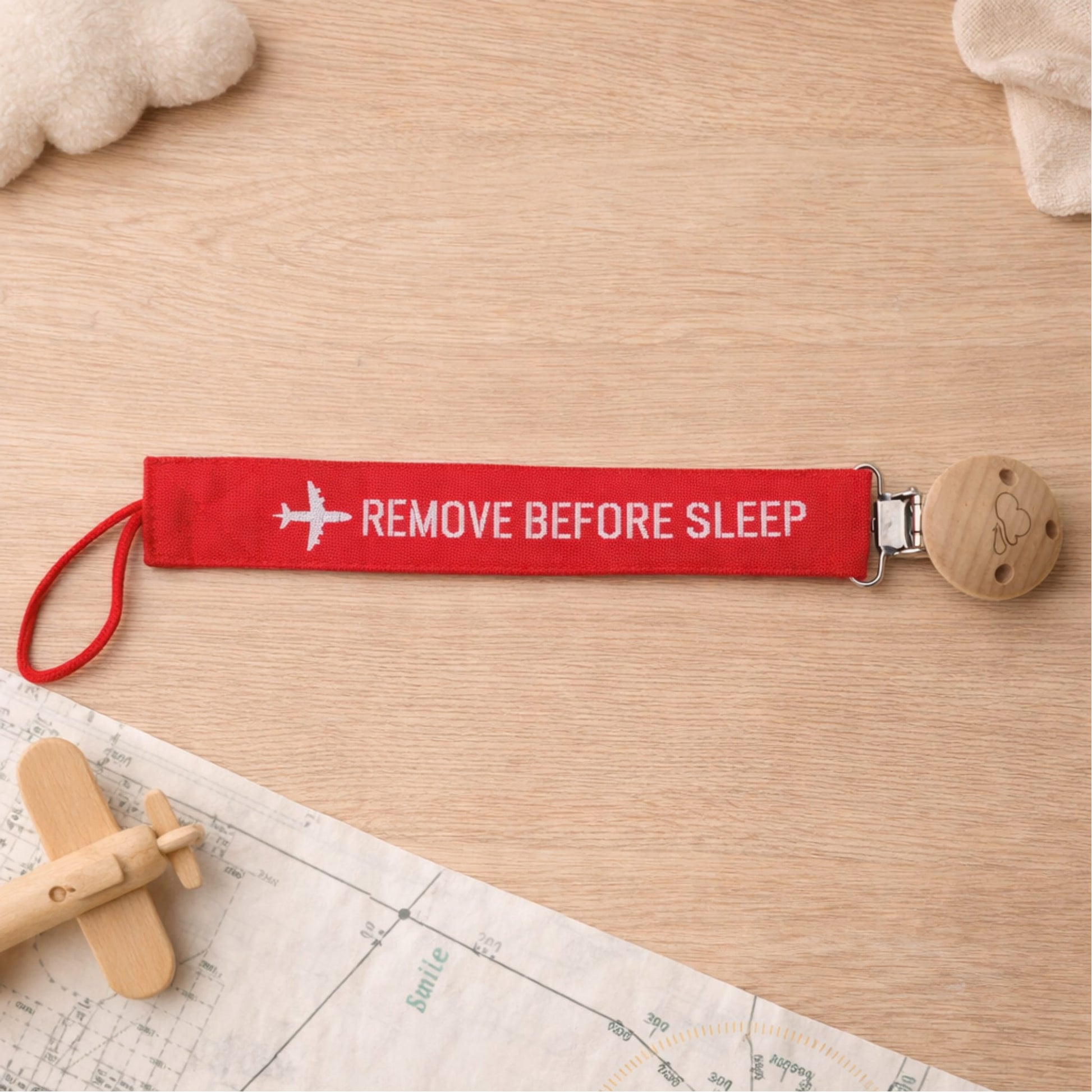 Baby pacifier clip with Remove Before Sleep aviation label in lifestyle setting